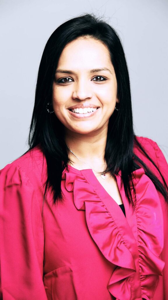 Headshot of Rekah Srivasan, VP Product Marketing, Salesforce | middle eastern business woman wearing pink blazerand blouse with brown hair, brown eyes, and smiling